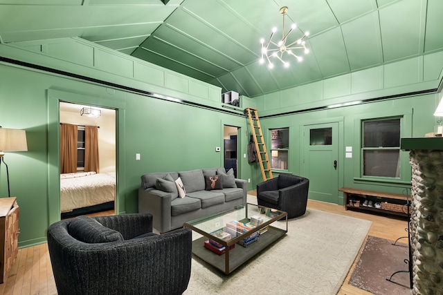 living room with a chandelier, lofted ceiling, and wood finished floors