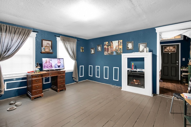 office space with a textured ceiling, a lit fireplace, and wood finished floors