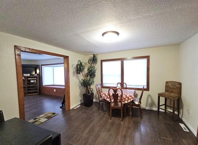 dining room featuring visible vents, dark wood finished floors, a textured ceiling, and baseboards