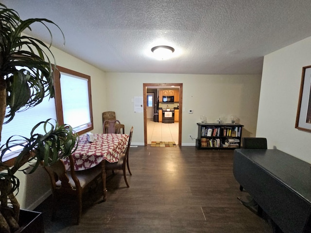 dining room featuring a textured ceiling, dark wood-style flooring, and baseboards