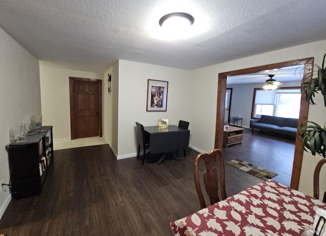 dining space with a textured ceiling, baseboards, and dark wood-type flooring