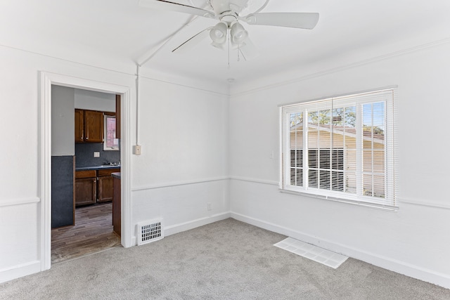 spare room featuring baseboards, carpet flooring, visible vents, and a ceiling fan