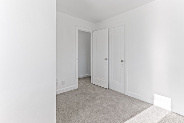 unfurnished bedroom with light carpet and baseboards