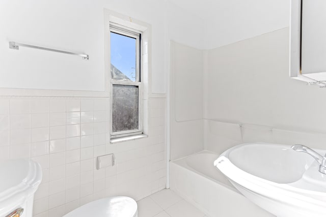 full bath with toilet, tile patterned floors, a sink, tile walls, and shower / bathing tub combination