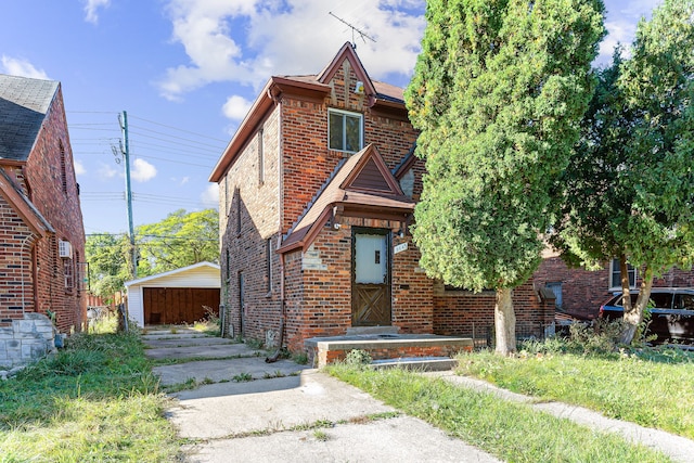 tudor-style house featuring an outbuilding, brick siding, and a detached garage