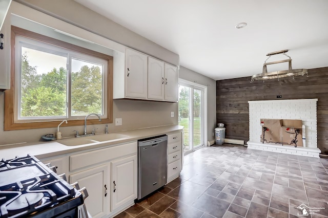 kitchen featuring light countertops, white cabinets, wood walls, a sink, and dishwasher