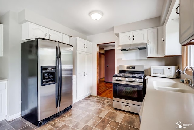 kitchen with appliances with stainless steel finishes, white cabinetry, a sink, and under cabinet range hood