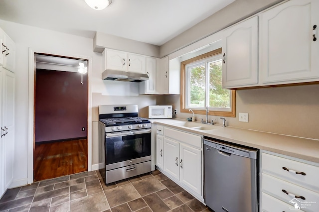 kitchen with stainless steel appliances, light countertops, under cabinet range hood, white cabinetry, and a sink