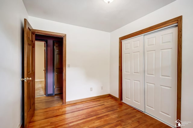 unfurnished bedroom with a closet, baseboards, and wood finished floors