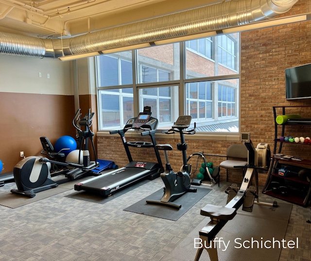 exercise area with brick wall and carpet flooring