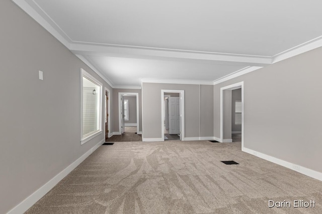 carpeted spare room with ornamental molding, visible vents, and baseboards