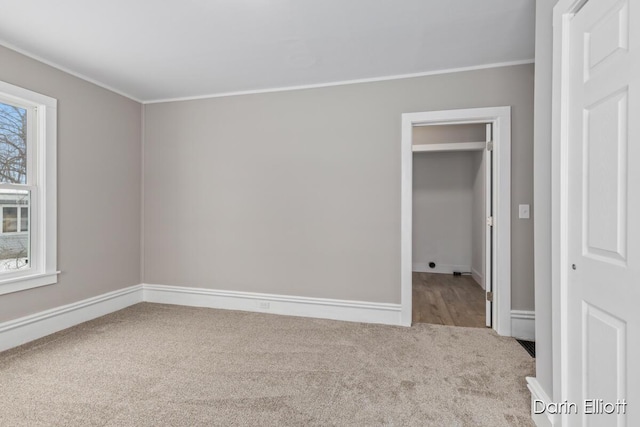 spare room with light carpet, baseboards, and ornamental molding