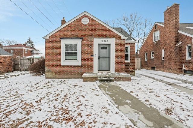 bungalow featuring brick siding and a chimney