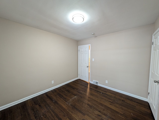 spare room with visible vents, dark wood finished floors, and baseboards