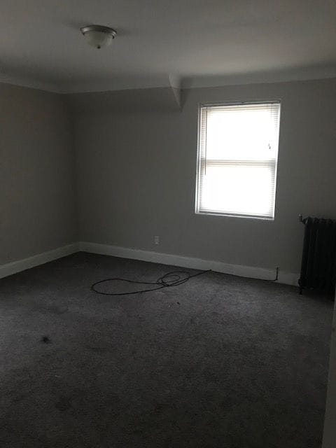 spare room with carpet floors, radiator, and baseboards