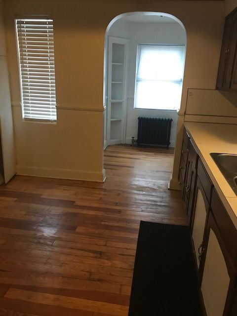 interior space with arched walkways, dark wood finished floors, light countertops, radiator heating unit, and a sink