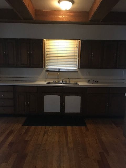 kitchen featuring dark wood-style flooring, light countertops, a sink, and dark brown cabinets