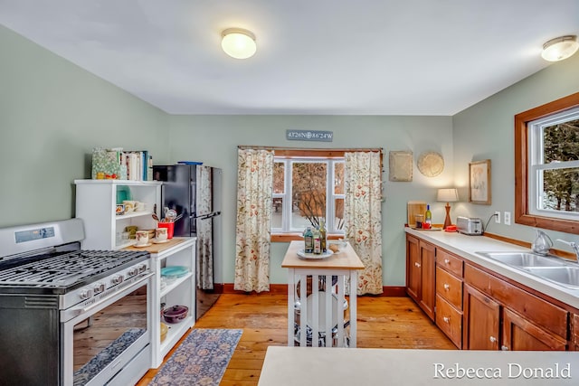 kitchen with brown cabinets, light countertops, a healthy amount of sunlight, and stainless steel range with gas stovetop