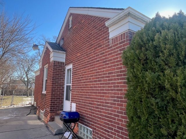 view of side of property featuring brick siding, a patio, and fence