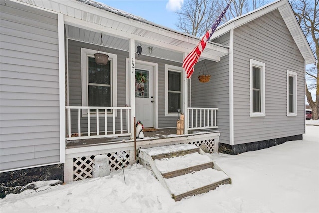 snow covered property entrance with covered porch