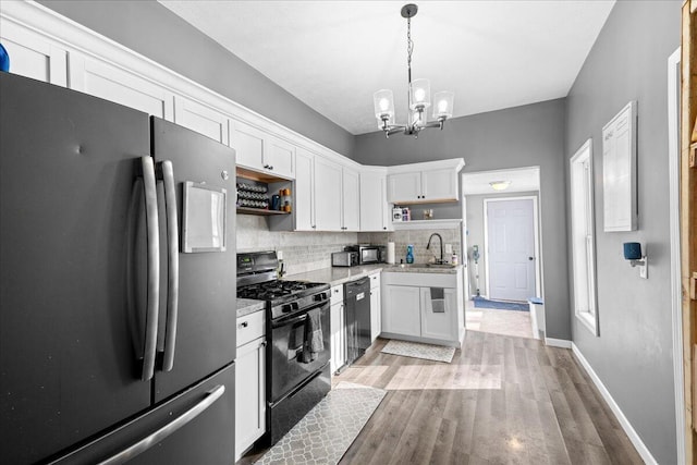 kitchen with open shelves, a sink, white cabinets, hanging light fixtures, and black appliances