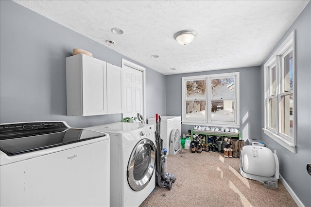 washroom featuring cabinet space, baseboards, light colored carpet, independent washer and dryer, and a textured ceiling