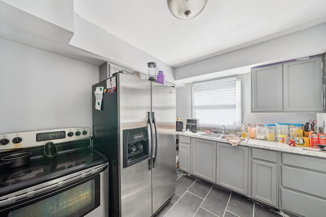 kitchen featuring appliances with stainless steel finishes, gray cabinets, a sink, and dark tile patterned floors