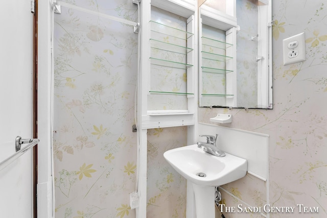 bathroom with wallpapered walls and a sink