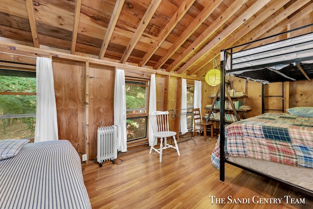 bedroom featuring wooden walls, radiator, wooden ceiling, wood finished floors, and vaulted ceiling