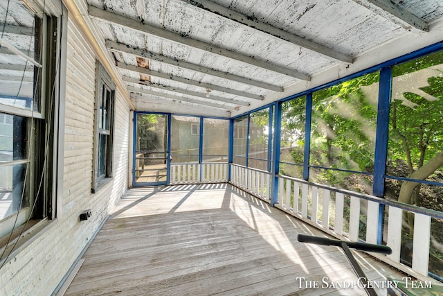 unfurnished sunroom featuring beam ceiling