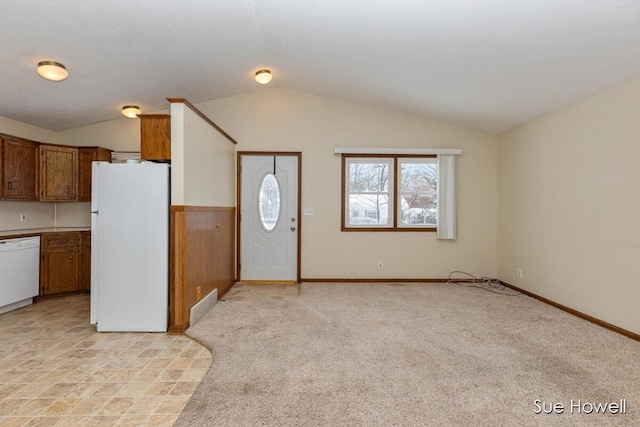 foyer entrance featuring light carpet, baseboards, visible vents, and vaulted ceiling