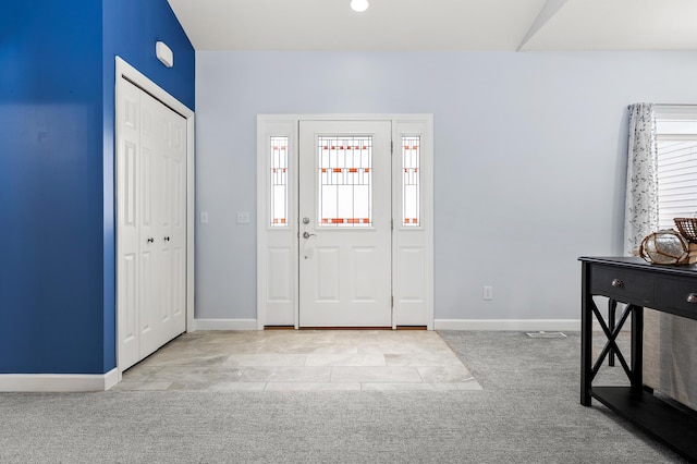 foyer with baseboards and light colored carpet