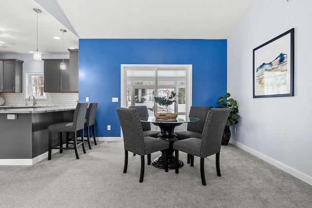 dining room featuring lofted ceiling, baseboards, and light colored carpet