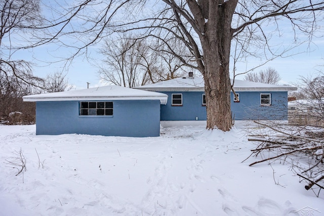 snow covered house featuring stucco siding