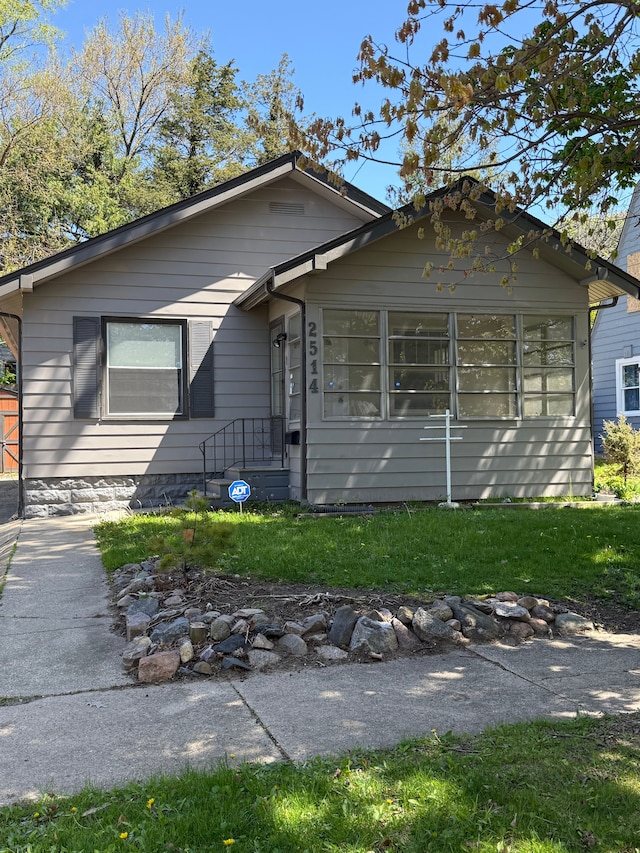 view of front facade featuring a sunroom and a front yard