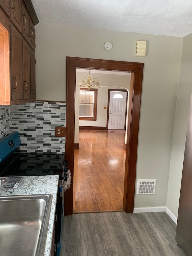 kitchen featuring wood finished floors, backsplash, baseboards, stainless steel range with electric stovetop, and light countertops