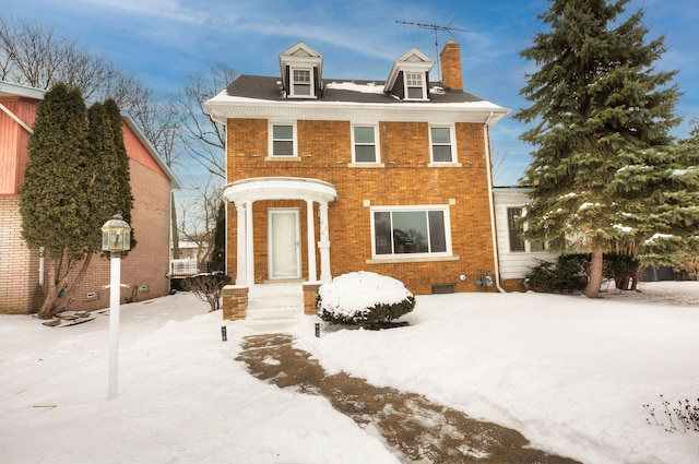 view of front facade with crawl space, brick siding, and a chimney