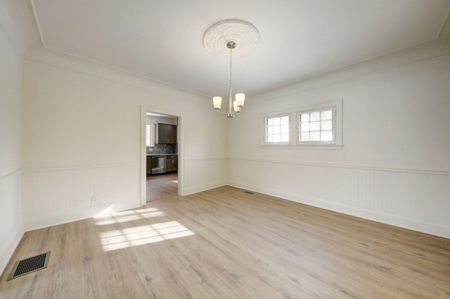 9543 W Outer Dr, Detroit, MI 48223 - spare room featuring a wainscoted wall, visible vents, light wood-type flooring, baseboards, and a chandelier