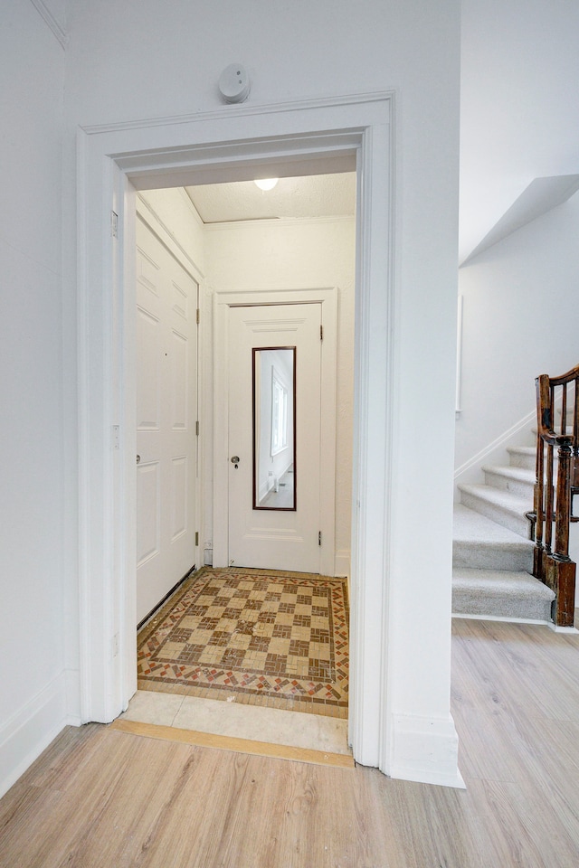 corridor featuring light wood-type flooring and stairs