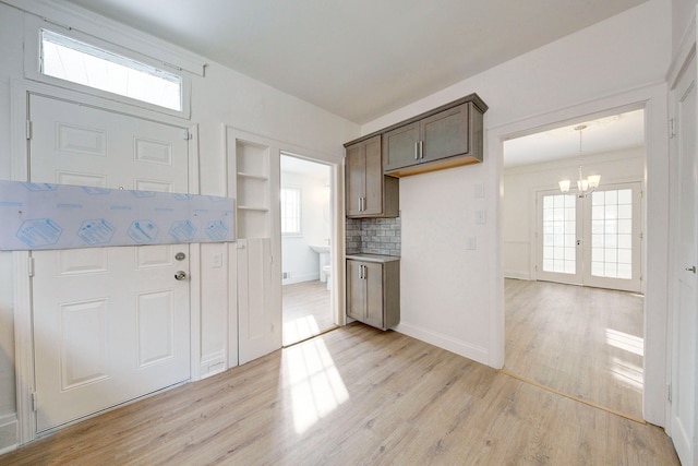 9543 W Outer Dr, Detroit, MI 48223 - kitchen with dark brown cabinets, decorative backsplash, light wood-style floors, baseboards, and a notable chandelier