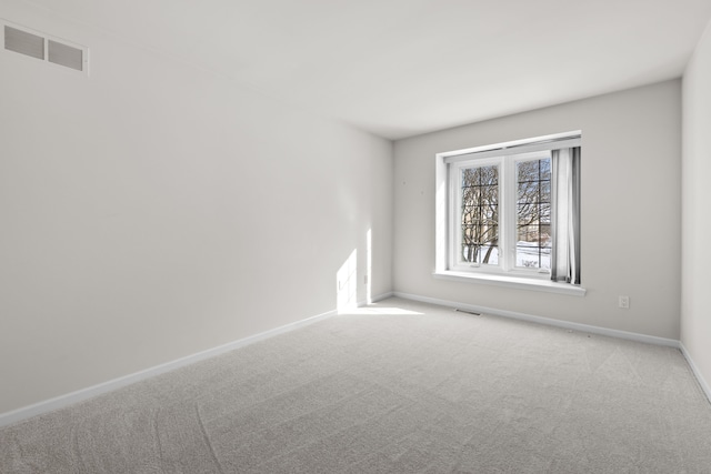 spare room featuring visible vents, light carpet, and baseboards