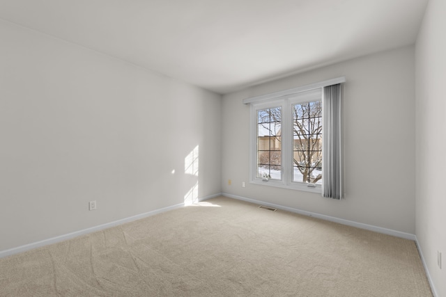 empty room featuring visible vents, light carpet, and baseboards