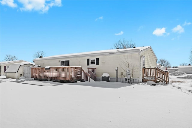 snow covered back of property with a wooden deck