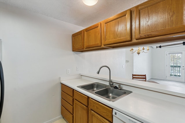 kitchen featuring brown cabinets, light countertops, a sink, a textured ceiling, and white dishwasher