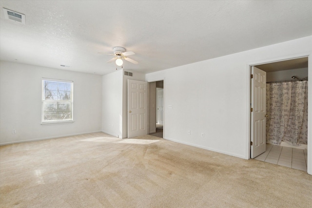 unfurnished bedroom featuring a textured ceiling, baseboards, visible vents, and light colored carpet