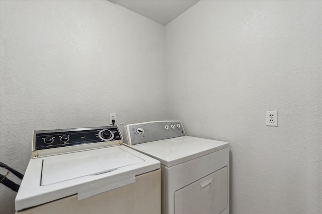 clothes washing area featuring a textured wall, laundry area, and washing machine and clothes dryer