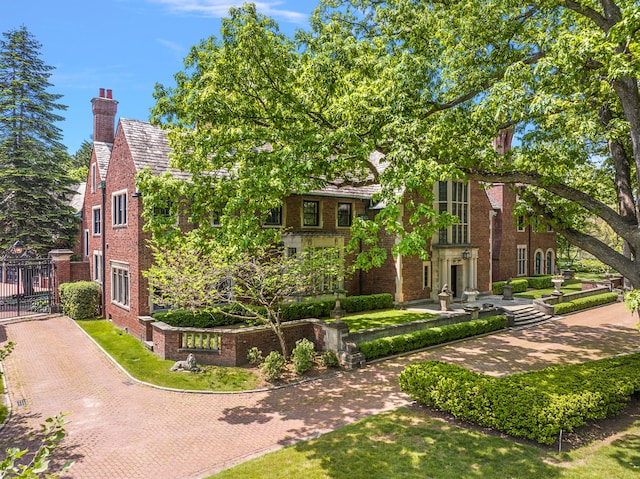 1771 Balmoral Dr, Detroit, MI 48203 - view of front facade featuring decorative driveway, brick siding, a chimney, and a gate