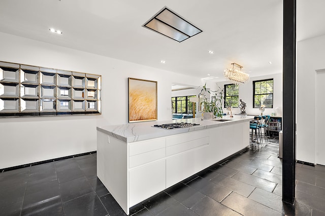 1771 Balmoral Dr, Detroit, MI 48203 - kitchen with a center island, stainless steel gas cooktop, recessed lighting, an inviting chandelier, and white cabinetry