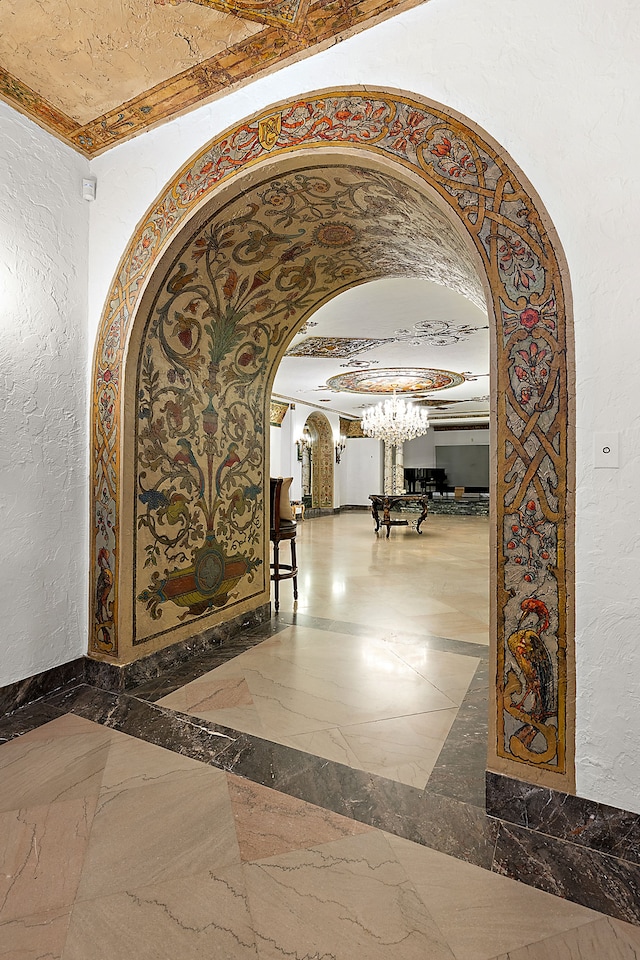 1771 Balmoral Dr, Detroit, MI 48203 - hallway with arched walkways, a notable chandelier, marble finish floor, and a textured wall
