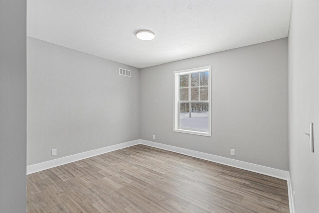 unfurnished room with visible vents, baseboards, and wood finished floors